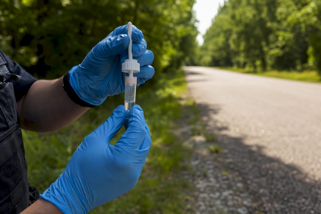 Mains de policiers tenant un test salivaire de dépistage de drogues